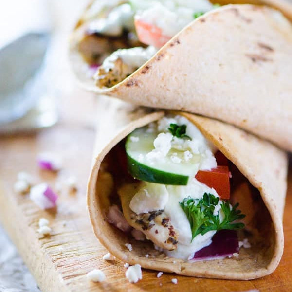 Souvlaki chicken wrap with grilled chicken pieces with tomato, pickled red onion, cucumber, tzatziki + greens