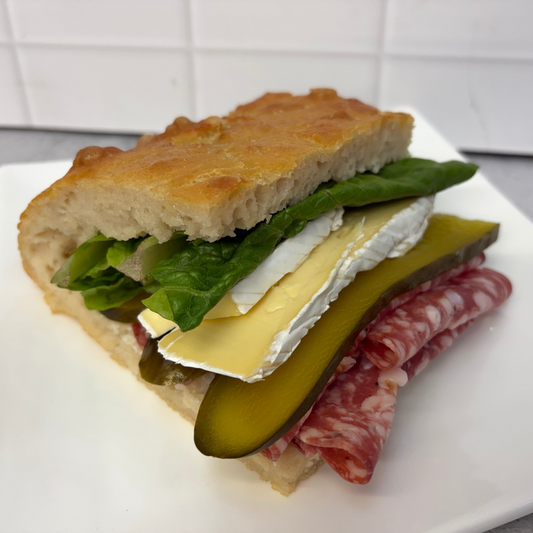 Focaccia sandwich with salami, pickle, Whitestone brie, lettuce + mayo