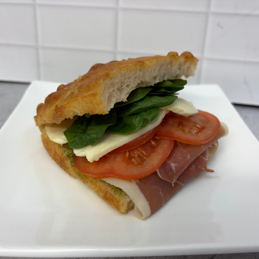 Focaccia sandwich with pesto, prosciutto, fresh tomato, mozzarella, basil and aioli