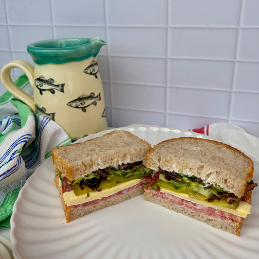 Tasty salami sandwich with mayo, salami, brie, pickle + crunchy lettuce on grain sourdough